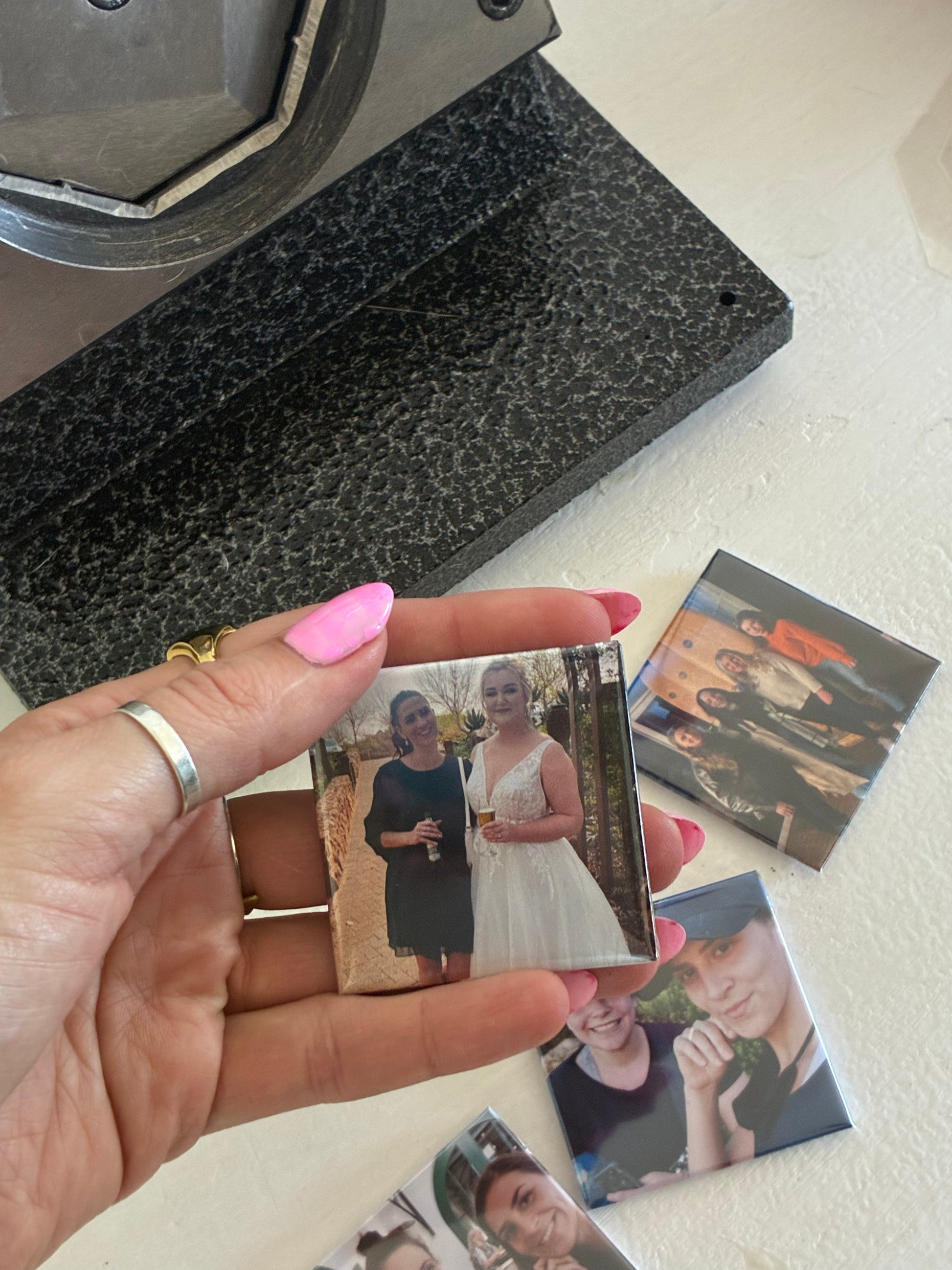 Hand holding a small photo of two women, with more photos on a surface below.